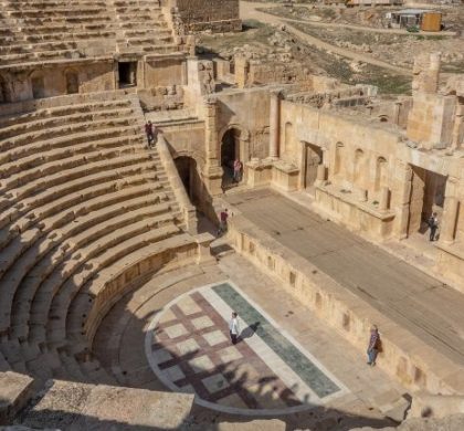 A high angle shot of two people standing in an ancient amphitheater during daytime