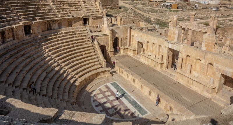 A high angle shot of two people standing in an ancient amphitheater during daytime